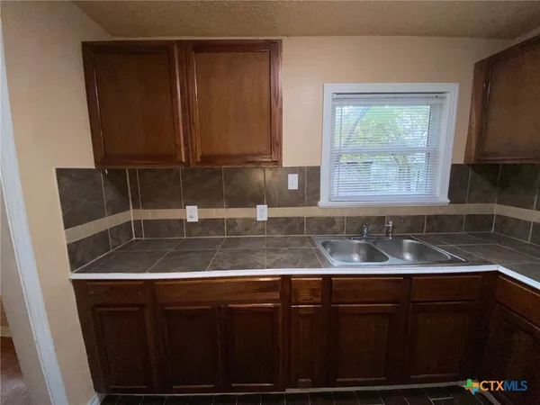 a kitchen with granite countertop a sink a stove and cabinets
