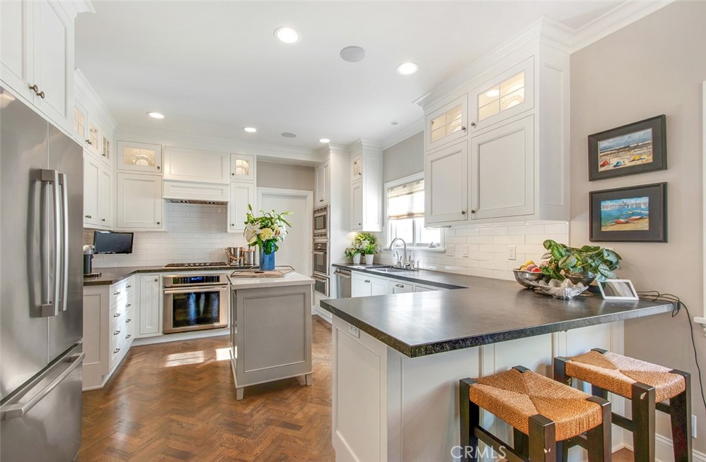 213 Via Firenze Newport Beach, CA 92663 - Photo 10 of 41 a kitchen with a stove a sink dishwasher a refrigerator and a dining table with wooden floor