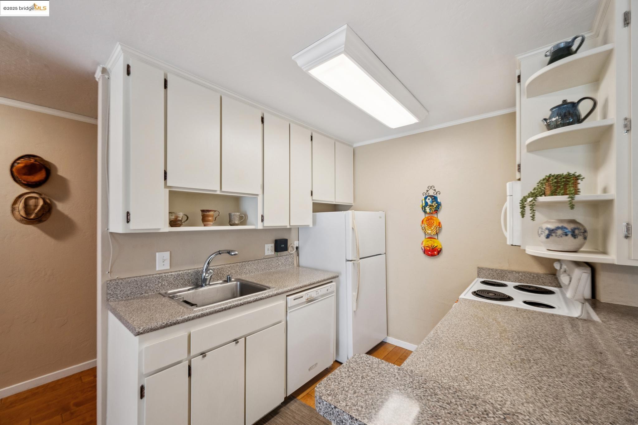 250 Whitmore Street Oakland, CA 94611 - Photo 18 of 33 Kitchen featuring open shelves, ornamental molding, light countertops, white appliances, and white cabinets