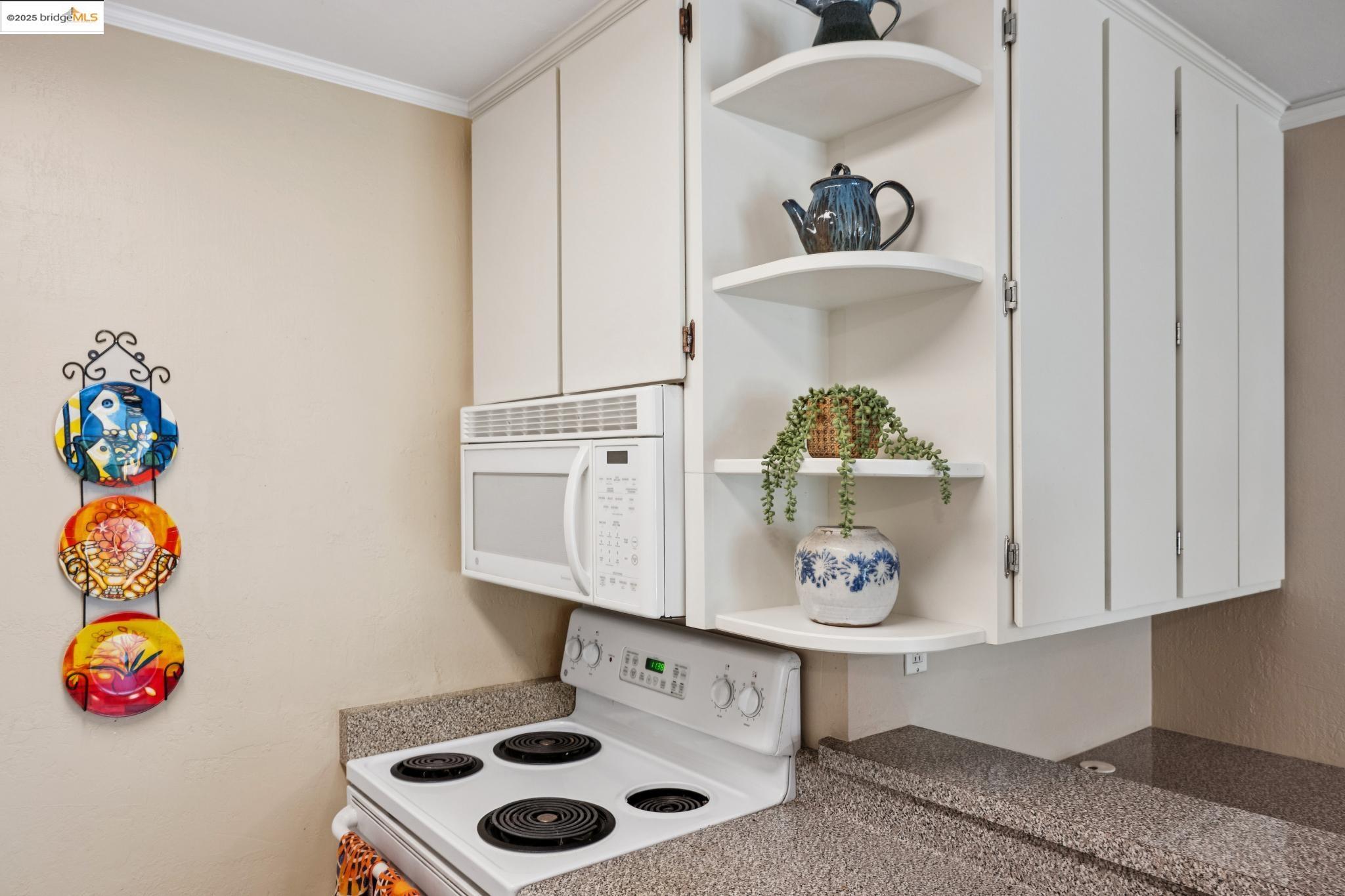 250 Whitmore Street Oakland, CA 94611 - Photo 20 of 33 Kitchen view of open shelves, white appliances, crown molding, and white cabinetry