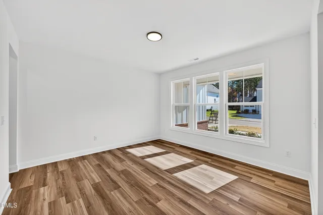 a view of an empty room with wooden floor fireplace and a window