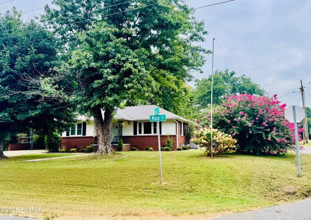 a front view of a house with a big yard and potted plants
