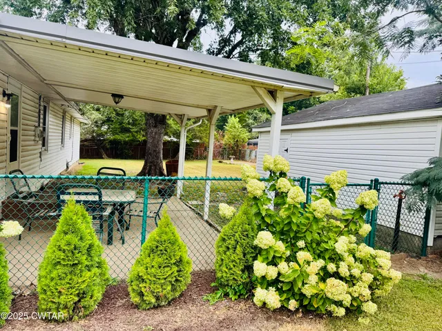a view of a patio with table and chairs potted plants and large tree