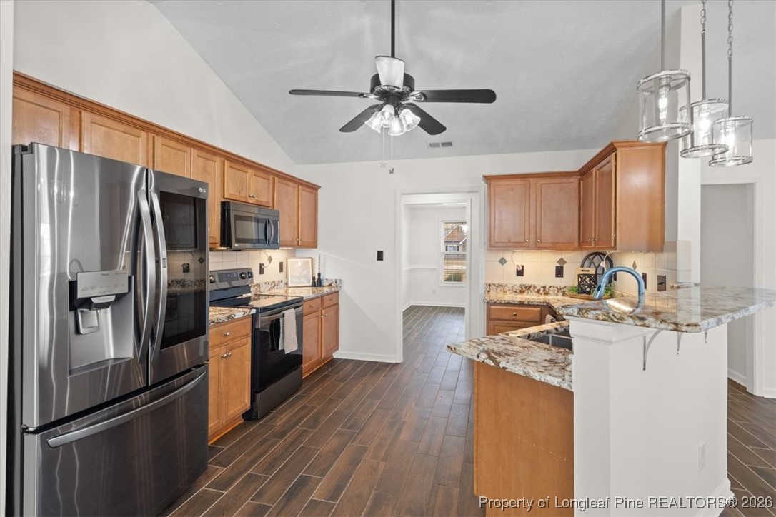 6649 Hillbrook Road Hope Mills, NC 28348 - Photo 15 of 37 a kitchen with stainless steel appliances granite countertop a refrigerator a stove top oven a sink dishwasher and white cabinets with wooden floor