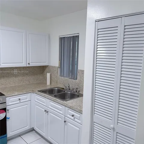 a kitchen with white cabinets and sink
