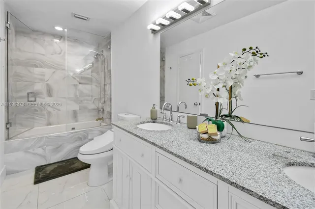 a bathroom with a granite countertop sink a toilet and shower