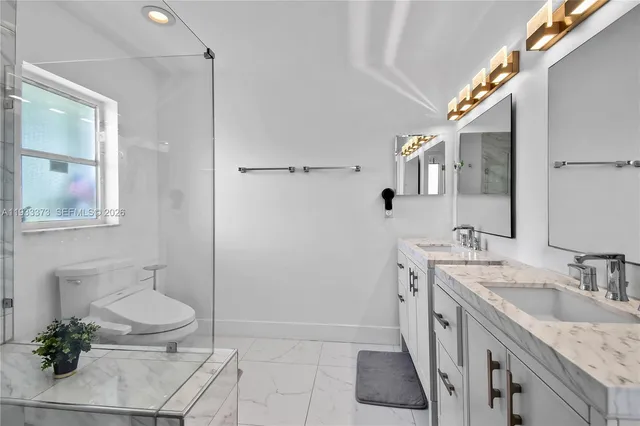 a spacious bathroom with a granite countertop sink a toilet a mirror and vanity