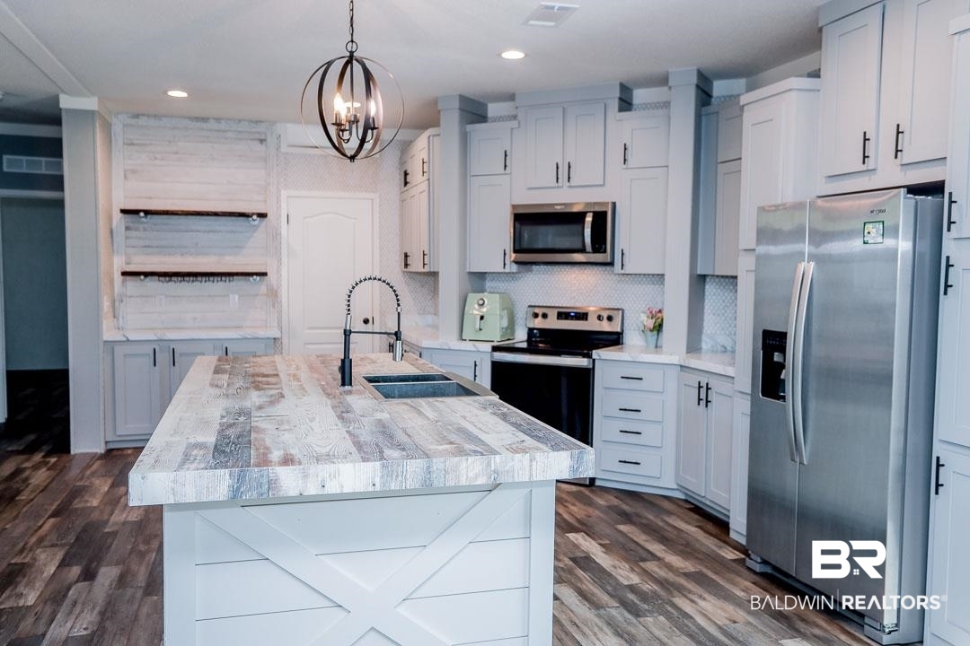 19180 Horseshoe Circle Seminole, AL 36574 - Photo 8 of 38 Kitchen featuring appliances with stainless steel finishes, a center island with sink, backsplash, hanging light fixtures, and dark wood finished floors