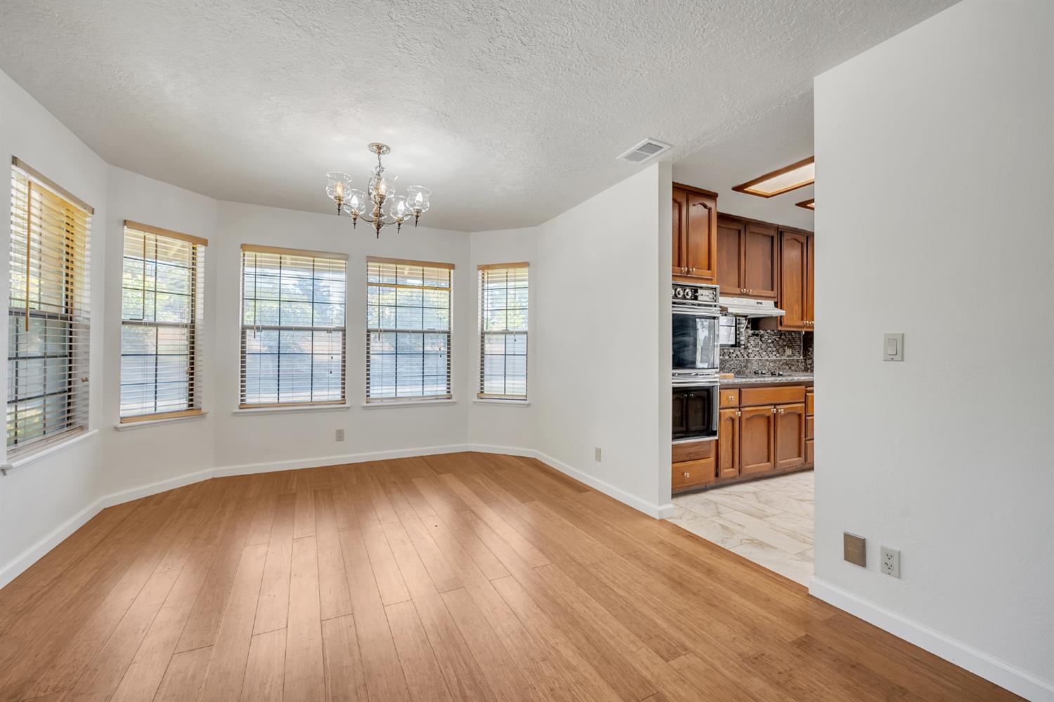 5990 Barton Road Loomis, CA 95650 - Photo 17 of 67 an empty room with wooden floor chandelier and windows