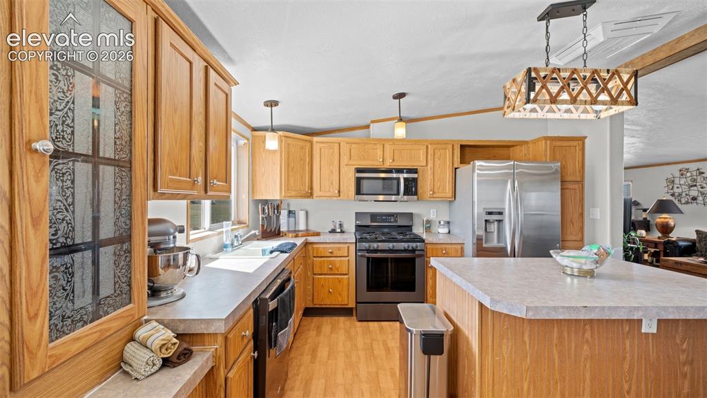 33975 Highway 94 Yoder, CO 80864 - Photo 11 of 40 Kitchen featuring wood-finish cabinetry, stainless steel appliances, a center island with a composite countertop, and wood-finish flooring