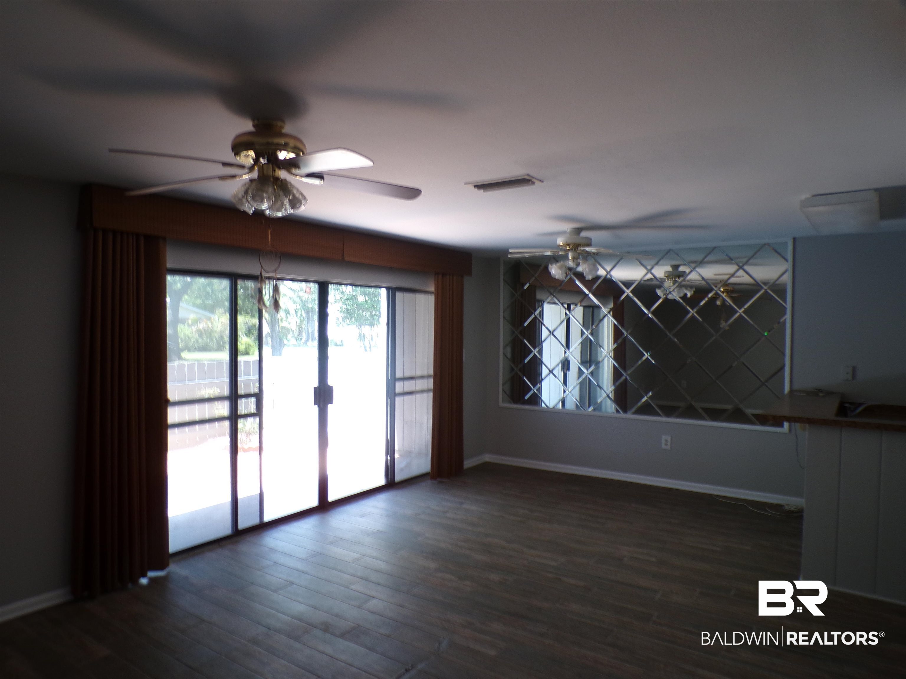 1152 North Alston Street, Unit 1152 Foley, AL 36535 - Photo 7 of 16 Room featuring wood-finish flooring, sliding glass doors with vertical blinds, and a built-in decorative mirrored wall