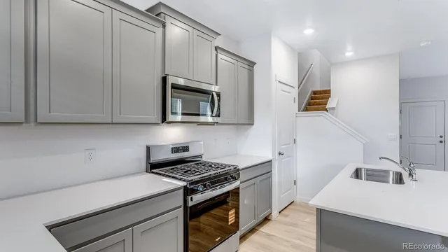 a kitchen with granite countertop a sink a stove top oven and cabinetry