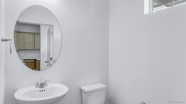 a bathroom with a toilet a sink and mirror