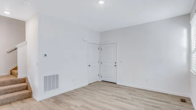 a view of an empty room with wooden floor and a potted plant
