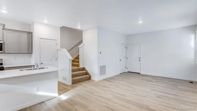 a view of an empty room with wooden floor and stairs