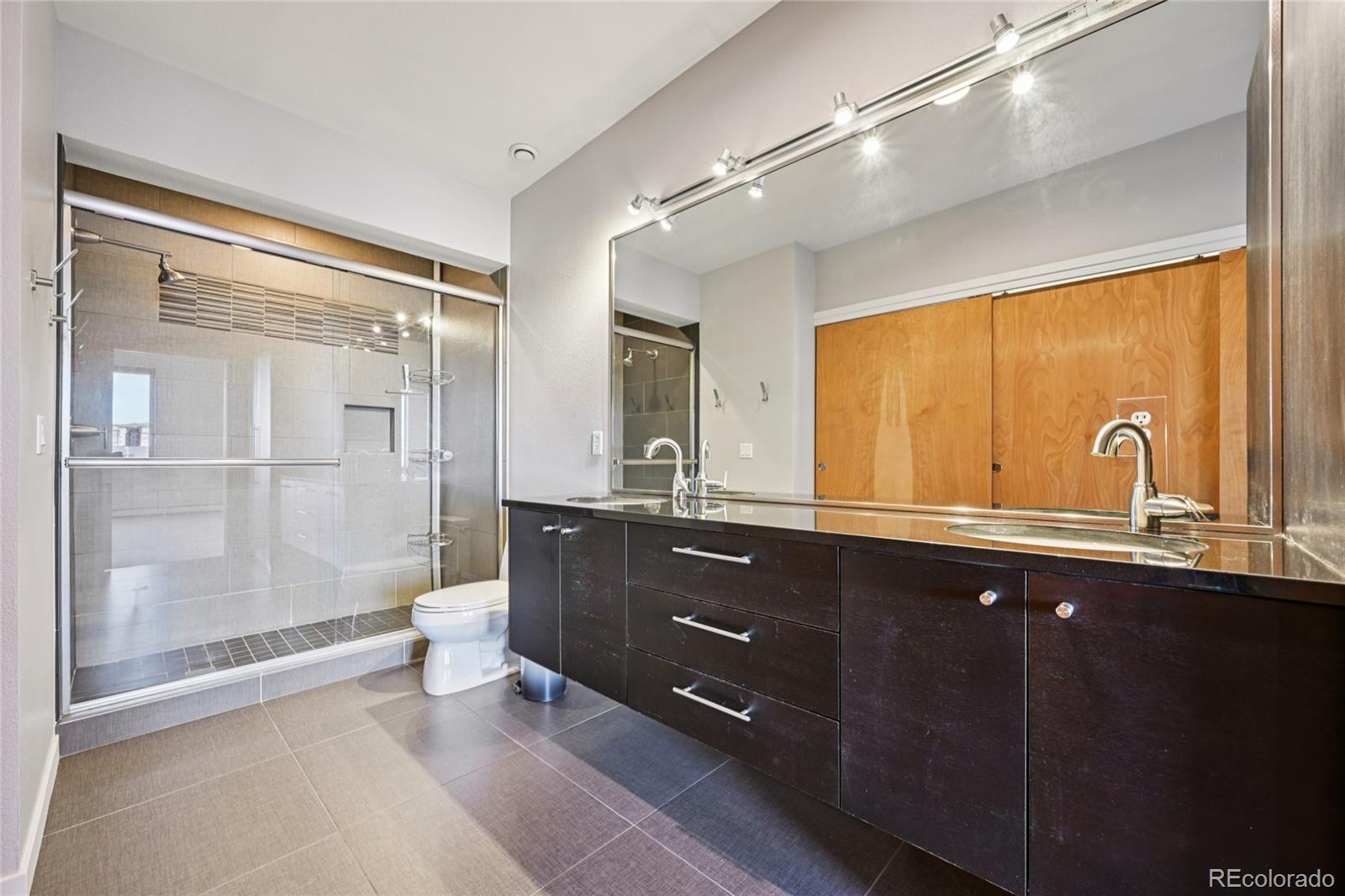 11562 Colony Row Broomfield, CO 80021 - Photo 35 of 48 a bathroom with a double vanity sink a large mirror and shower