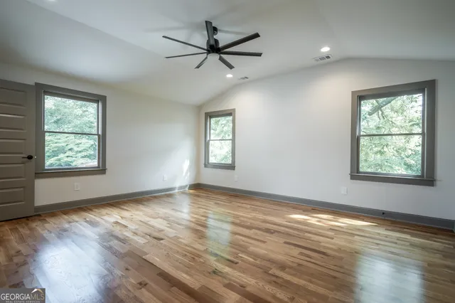 an empty room with wooden floor and windows