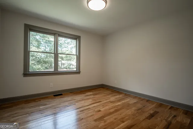 a view of an empty room with wooden floor and a window