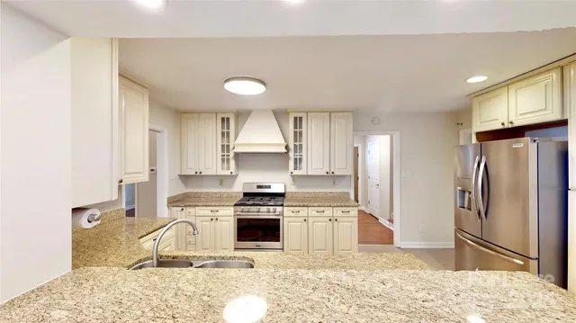 a kitchen with stainless steel appliances kitchen island granite countertop a refrigerator sink and stove