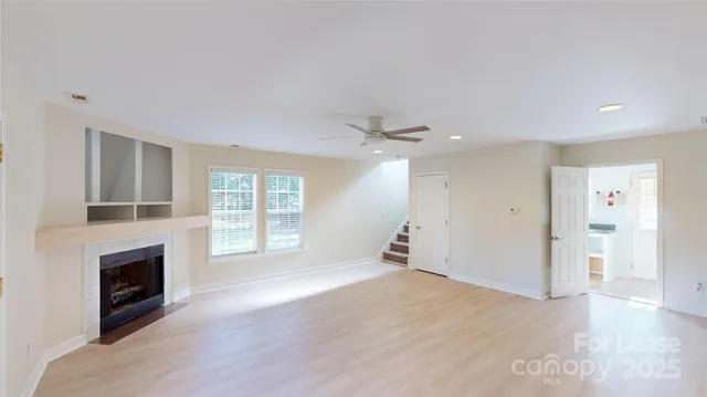 an empty room with windows and fireplace