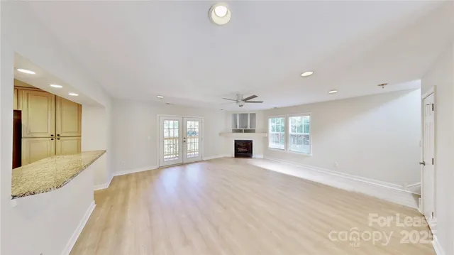 a view of an empty room with window and wooden floor