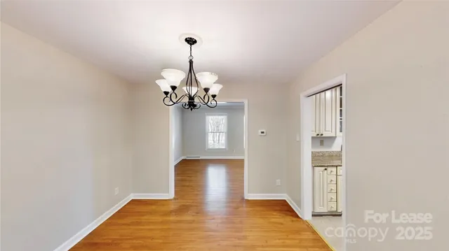 a view of a hallway with wooden floor and a chandelier
