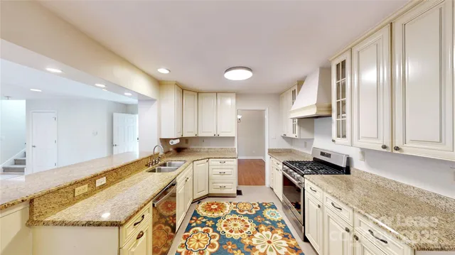 a large kitchen with stainless steel appliances granite countertop a sink and cabinets
