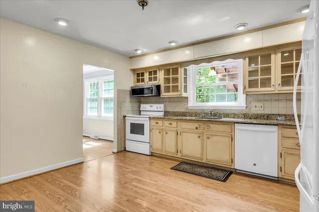 a kitchen with granite countertop a stove a sink and a microwave
