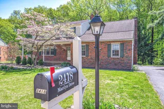 a front view of house with a garden and trees