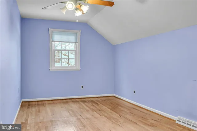 an empty room with a chandelier fan and windows