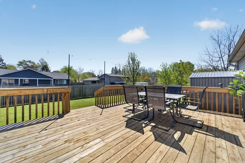 a view of a deck with chairs a barbeque with wooden floor and fence