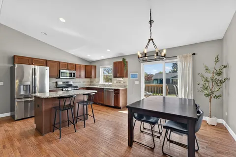 a kitchen with stainless steel appliances granite countertop a kitchen island hardwood floor and a sink