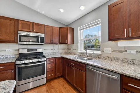 a kitchen with granite countertop a sink cabinets and stainless steel appliances