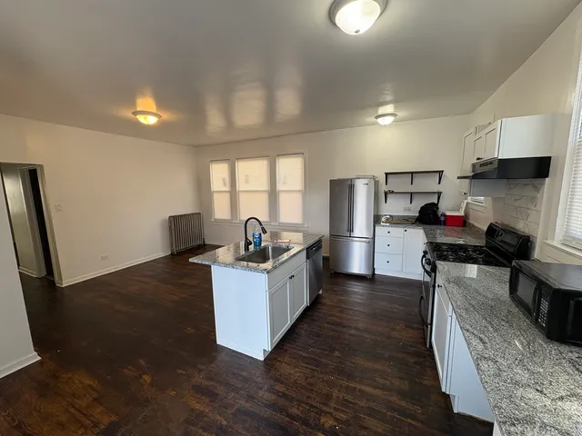 a kitchen with stainless steel appliances kitchen island granite countertop a sink a counter space and cabinets