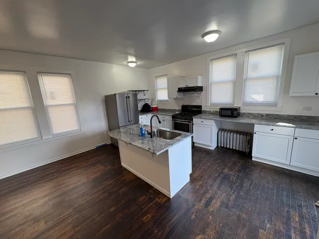 a kitchen with stainless steel appliances a stove top oven and a wooden floors