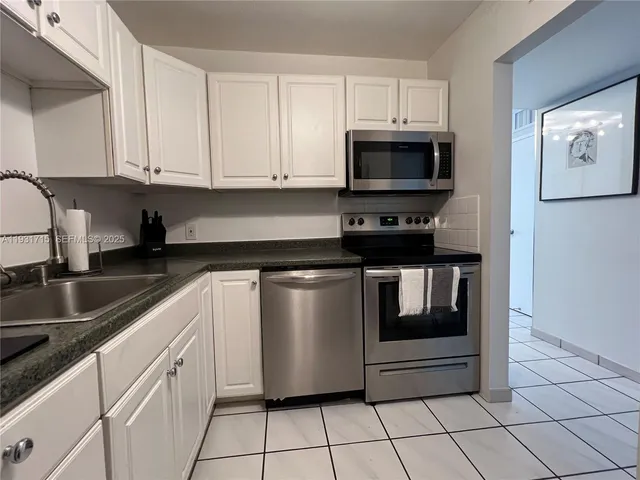 a kitchen with granite countertop white cabinets and refrigerator