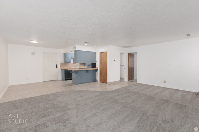 860 South Village Road, Unit A6 St. George, UT 84770 - Photo 4 of 41 Unfurnished living room featuring light carpet and a textured ceiling