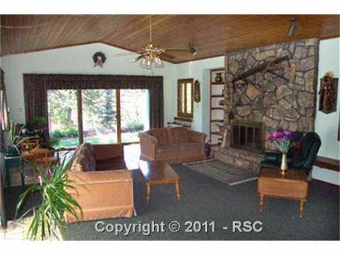 581 Mills Ranch Road Woodland Park, CO 80863 - Photo 4 of 16 Living room has two sets of sliders to walk out to deck or back yard. Moss rock gas fireplace and tongue and groove ceilings and to cozy warmth of room.