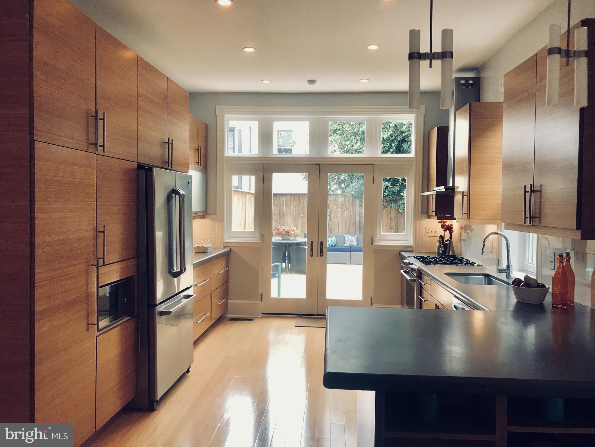 906 G Street Southeast Washington, DC 20003 - Photo 6 of 28 a kitchen with stainless steel appliances granite countertop a refrigerator a sink dishwasher a stove and a dining table with wooden floor