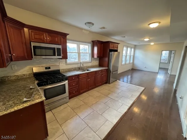 a large kitchen with stainless steel appliances granite countertop a stove top oven a sink dishwasher a dining table and chairs with wooden floor