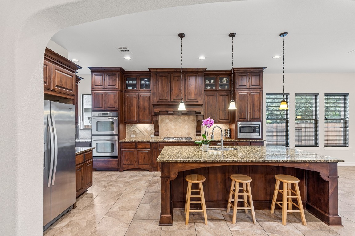 1916 Buffalo Speedway Leander, TX 78641 - Photo 13 of 30 a kitchen with stainless steel appliances granite countertop a stove refrigerator sink and cabinets