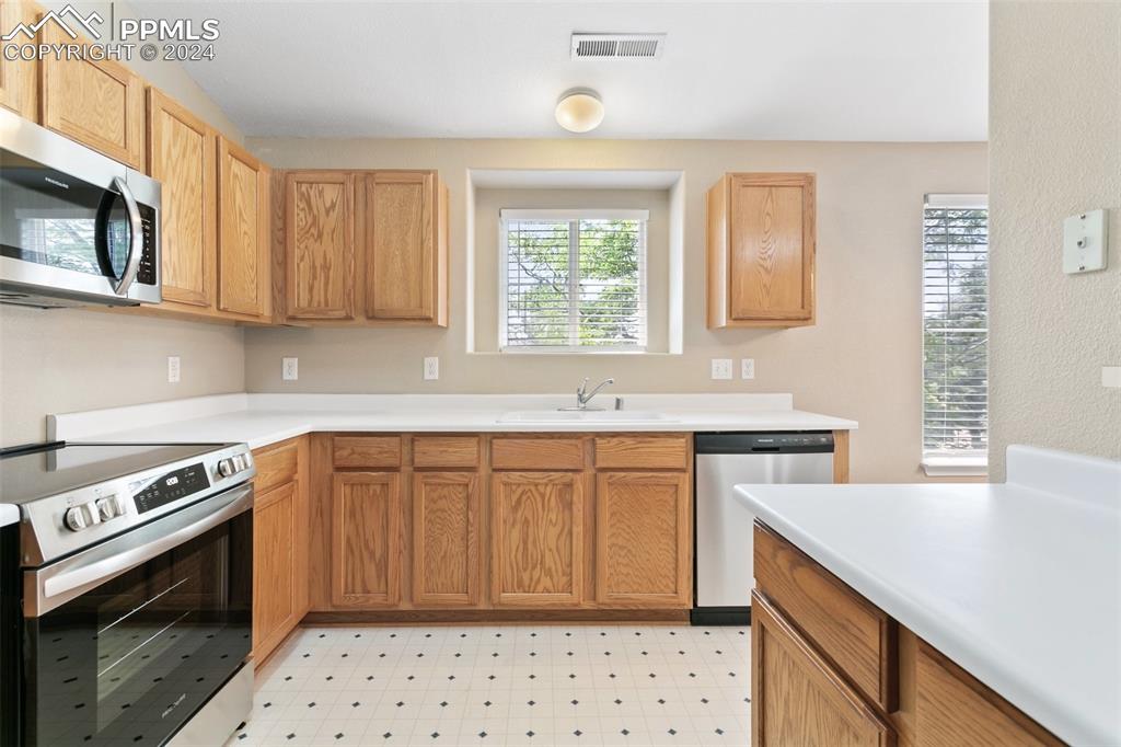 3831 Riviera Grove, Unit 204 Colorado Springs, CO 80922 - Photo 18 of 35 a kitchen with stainless steel appliances a stove a sink and a microwave