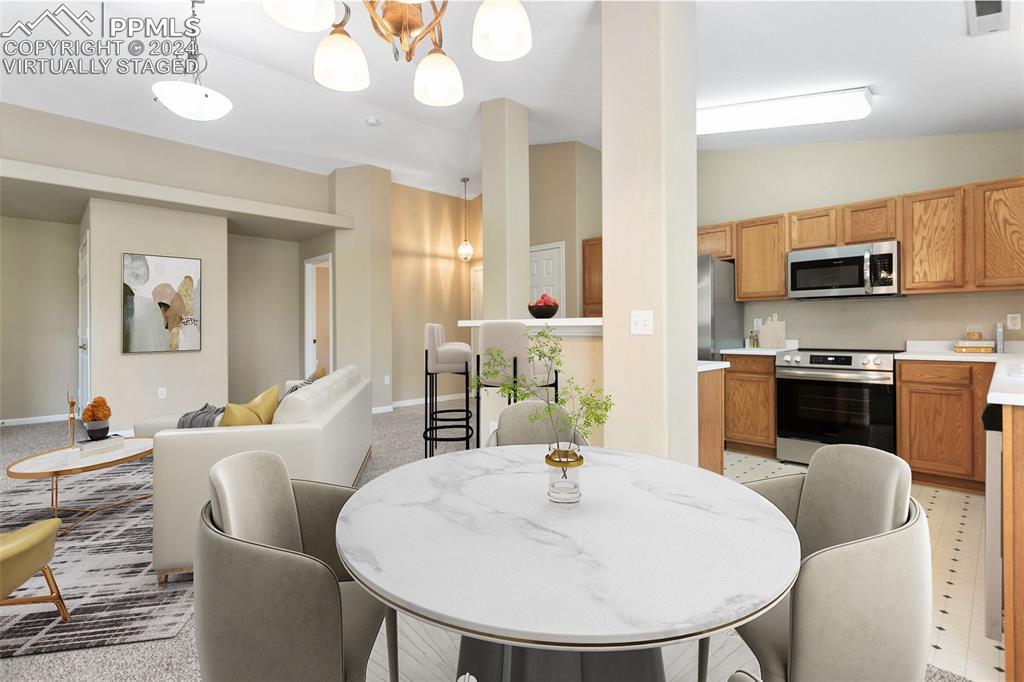 3831 Riviera Grove, Unit 204 Colorado Springs, CO 80922 - Photo 5 of 35 a kitchen with stainless steel appliances kitchen island granite countertop a sink a microwave a dining table and chairs