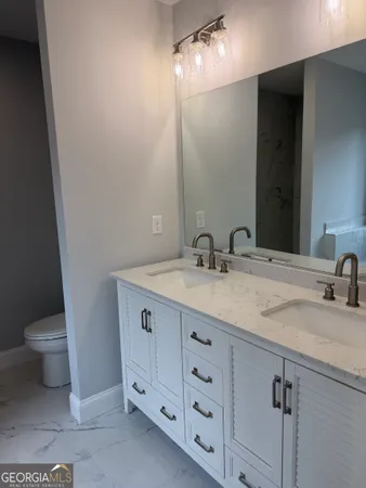 a bathroom with a granite countertop sink a toilet and a mirror