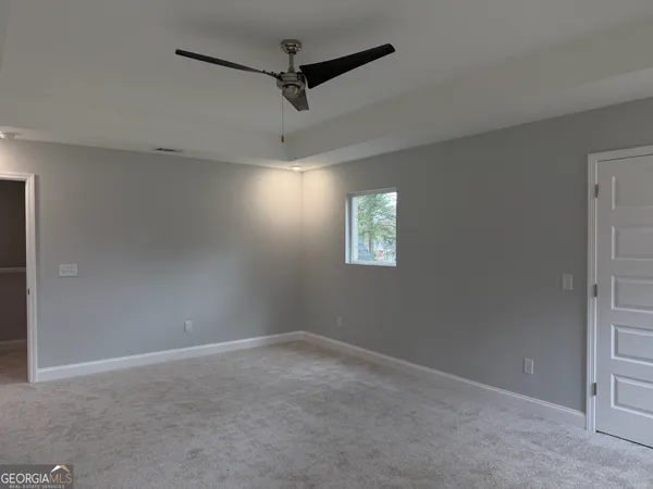 en empty room with windows and ceiling fan