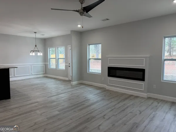an empty room with wooden floor a ceiling fan and windows