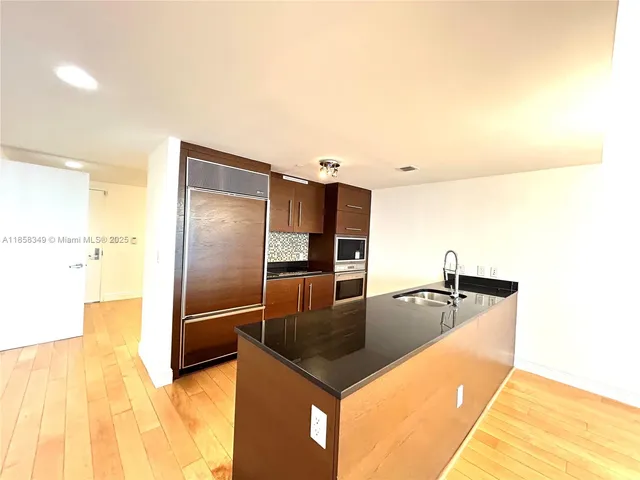 a kitchen with stainless steel appliances granite countertop a sink and a refrigerator