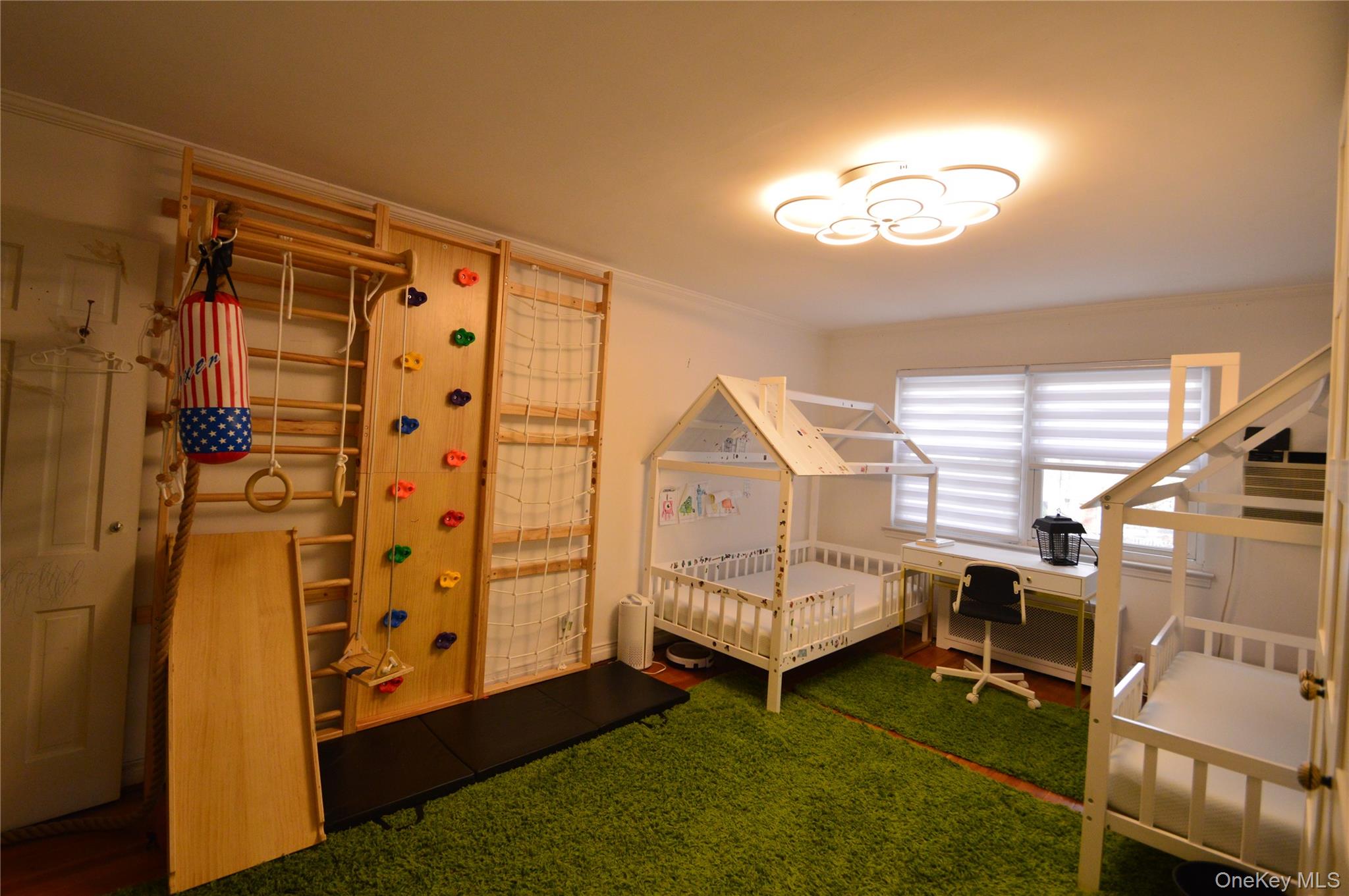 105-46 65th Road Queens, NY 11375 - Photo 11 of 20 a bedroom with a baby bed and a chandelier