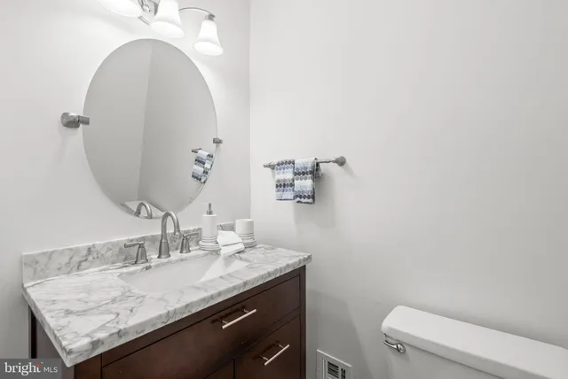 a bathroom with a granite countertop sink a toilet and a mirror
