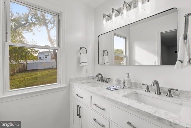 a bathroom with a granite countertop sink mirror and window